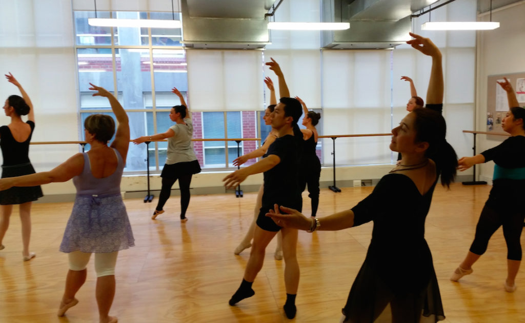 Adult Ballet Dancers in the studio in a ballet pose looking towards the front of the class
