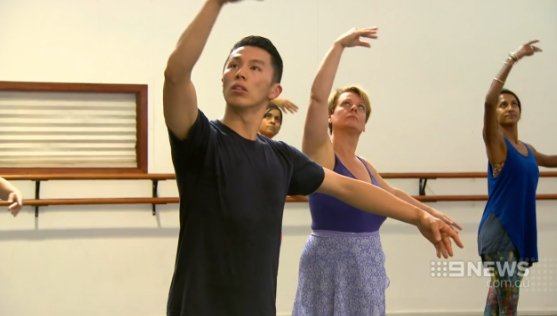 Adult dancers in a ballet class with arms up