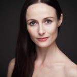 A portrait of Amber Scott, a ballet dancer and guest teacher at City Adult Ballet. The portrait is set against a dark background, contrasting Amber's pale skintone