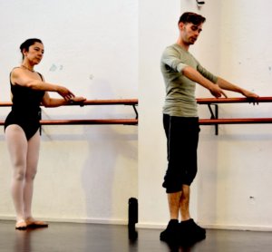 Male and female ballet dancer with arms in first position holding onto the ballet barre in the studio.